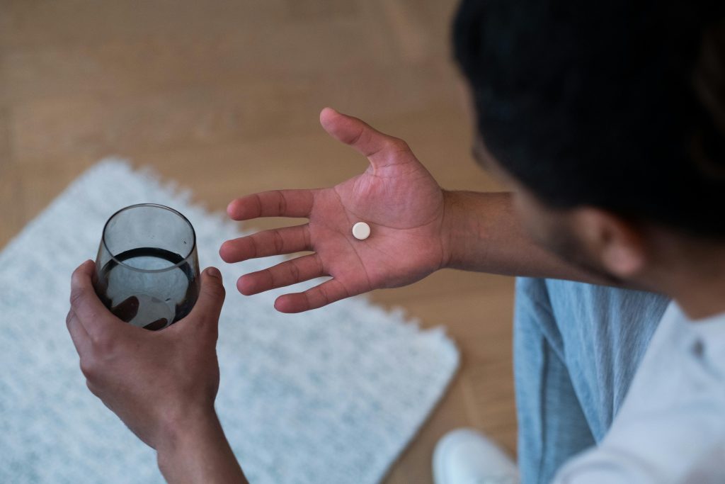 man holding pill and water