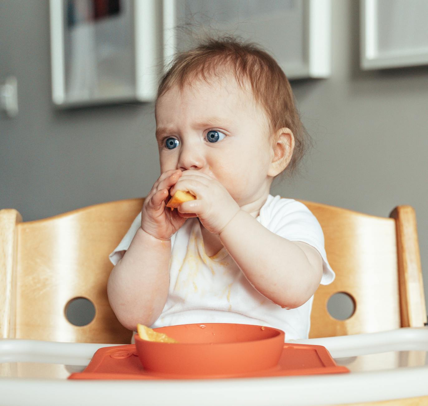 baby sitting in a feeding chair and eating