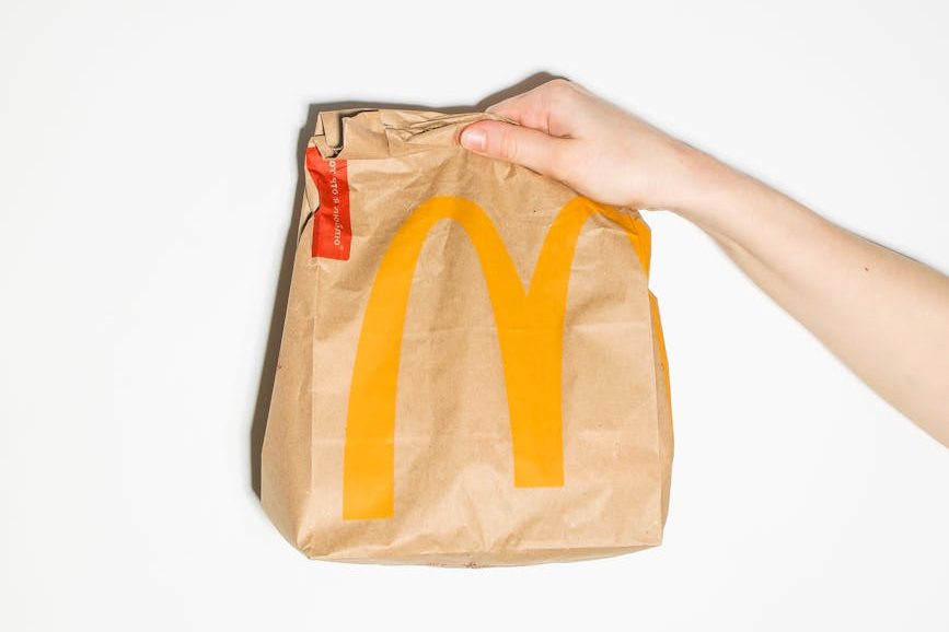 person holding brown and yellow paper bag