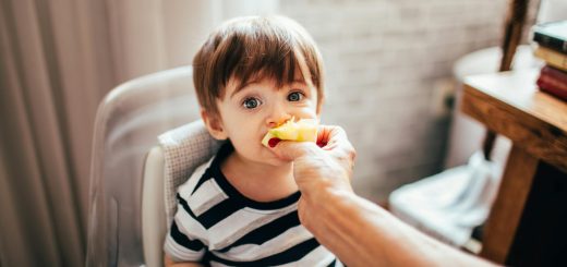 faceless parent feeding cute toddler