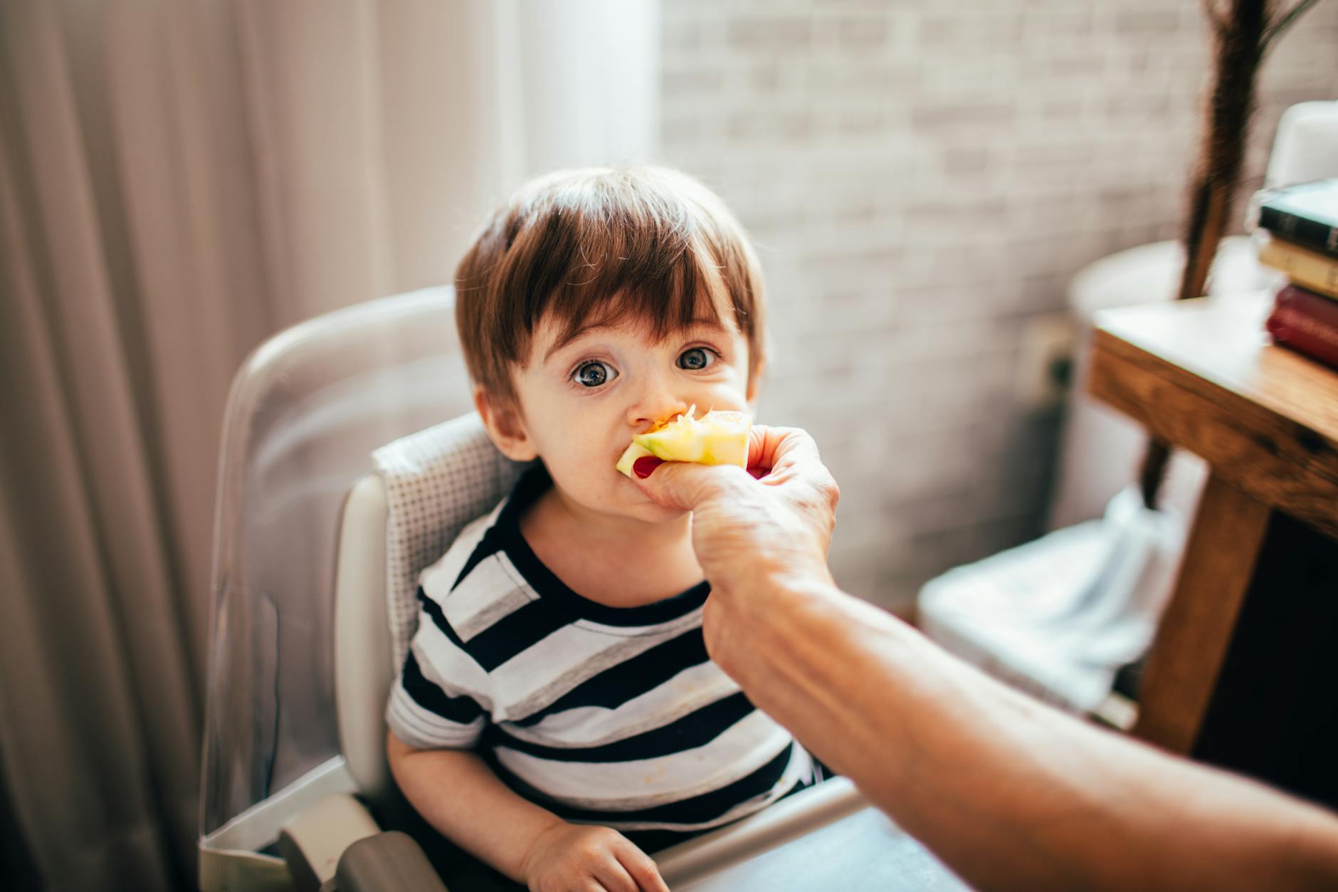 faceless parent feeding cute toddler